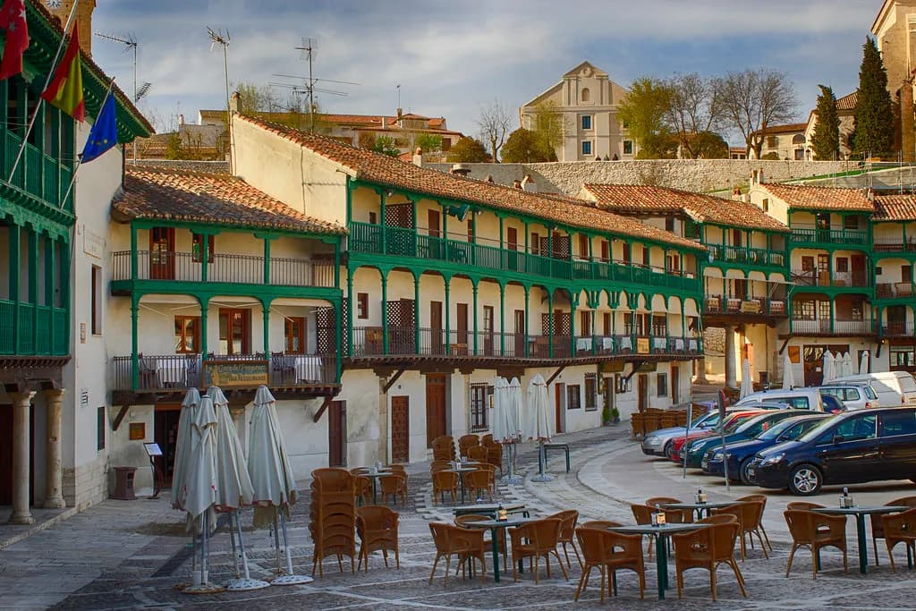 La Plaza Mayor porticada de Chinchón a última hora de la tarde, con las mesas de las terrazas bajo los balcones corridos de madera verde, en una excursión privada con chófer desde Madrid
